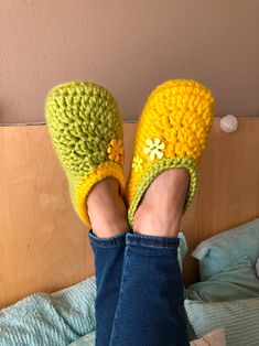 someone is wearing crocheted slippers and has their feet up on the bed