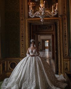 a woman in a wedding dress standing in front of a mirror and chandelier