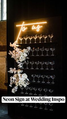 a lighted sign that says to us with wine glasses and flowers