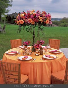 the table is set with orange and pink flowers