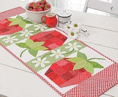 a table with a bowl of strawberries on it and a mug next to it