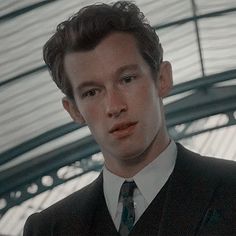 a man wearing a suit and tie in a room with glass ceilinged walls, looking at the camera