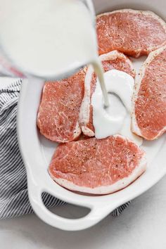 raw meat being poured into a bowl with milk on the side and napkins next to it