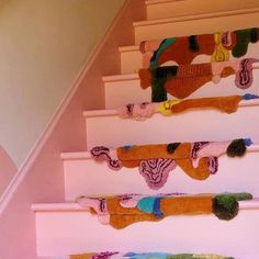 there is a set of stairs decorated with colorful knitted stockings on it's handrails