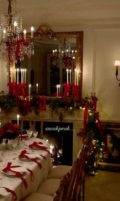 a dining room table set for christmas dinner with candles and red ribbon on the table