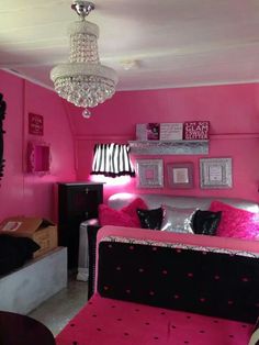 a pink room with black and white furniture, chandelier and pictures on the wall