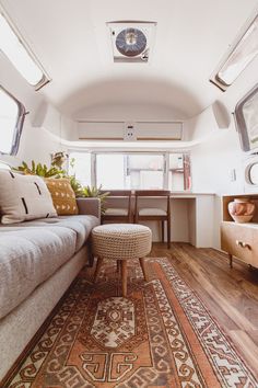 a living room with a couch, table and rugs on the floor in front of a window