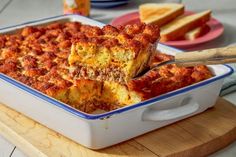 a casserole dish with meat and cheese in it on a wooden cutting board