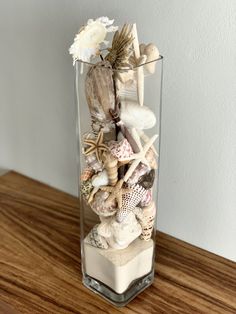 a vase filled with shells and seashells on top of a wooden table