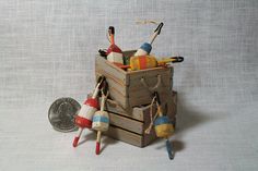 a small wooden box filled with different types of toy items next to a coin on a white surface