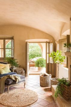 a living room filled with furniture and lots of plants on top of the fireplace mantel