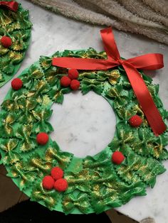 two christmas wreaths made out of green paper and red pom - poms