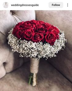 a bouquet of red roses and baby's breath is sitting on a couch next to a pillow