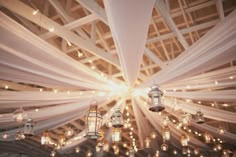 several lanterns are hanging from the ceiling in a room with white drapes and lights