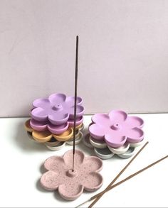 three flower shaped dishes with sticks sticking out of them on a white countertop next to some flowers