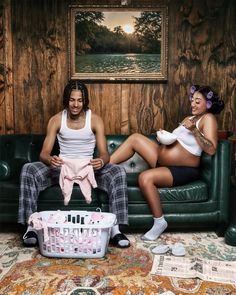 a man and woman sitting on a couch next to each other in front of a painting