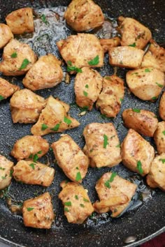 chicken and potatoes cooking in a pan on the stove top with parsley sprinkled around them