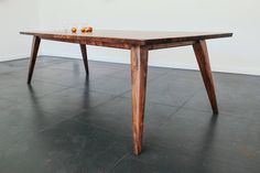 a wooden table sitting on top of a black floor next to a white wall and vases