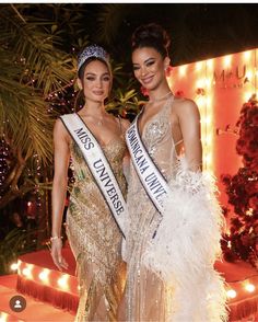 two beautiful women standing next to each other in front of some stairs with lights on them