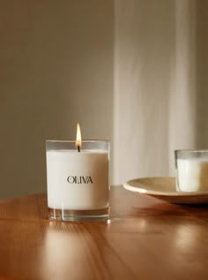 a candle sitting on top of a wooden table next to a cup and saucer