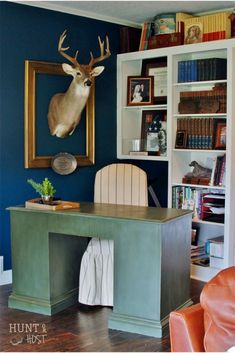 a desk with a deer head mounted on the wall above it in front of a bookshelf