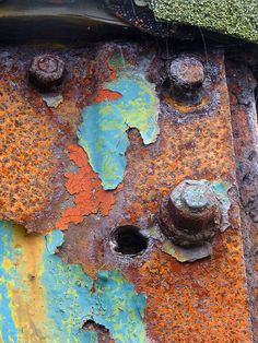 an old rusted metal surface with holes and rivets on the bottom part