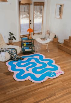 a blue and pink rug in the middle of a living room with wooden flooring