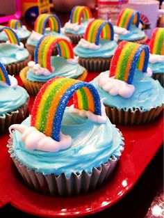 cupcakes with rainbow frosting and sprinkles are on a red plate