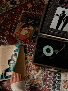 an old record player sitting on top of a rug next to a book and magazine