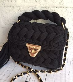 a black handbag with a gold buckle on the front and chain at the bottom