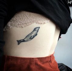 a woman's stomach with a small tattoo of a whale on the lower side