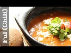 a black bowl filled with soup next to bread