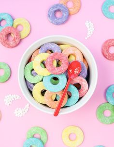 a bowl full of doughnuts and a spoon on a pink background with sprinkles