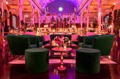 a room filled with green couches and tables in front of a purple lit ceiling