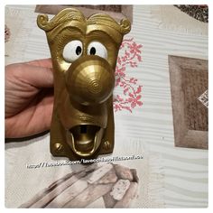 a hand holding a gold object with eyes and nose on top of a table cloth