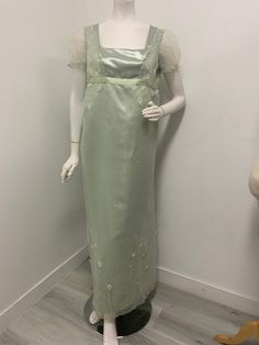 a mannequin wearing a green dress with white flowers on it's shoulders