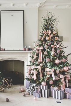 a decorated christmas tree sitting in front of a fire place with presents under the tree