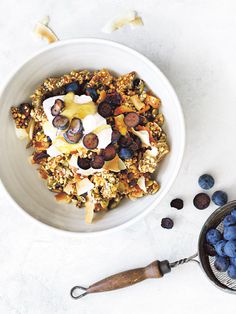 a bowl filled with granola and blueberries on top of a white countertop