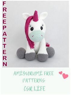 a crocheted stuffed unicorn with pink mane sitting on top of it's legs