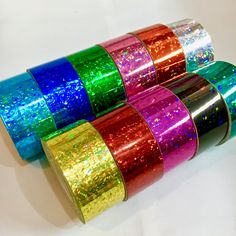 four rolls of colorful glitter tape on a white surface