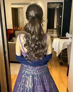 a woman standing in front of a mirror wearing a purple and blue dress with long hair