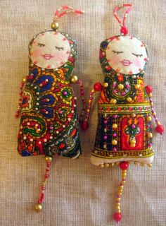 two ornaments made to look like cats with beads on their ears and tails, one has a cat's head in the middle