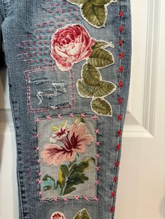 a pair of jeans with embroidered flowers on them