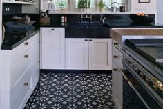 a kitchen with white cabinets and black counter tops is seen in this image from the doorway