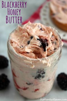 a dessert in a jar with berries and cream on the top, next to blackberries