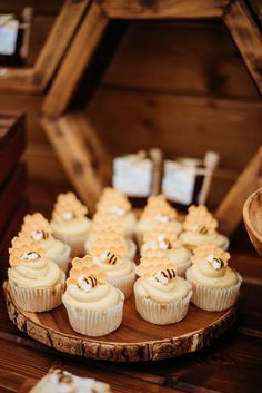 cupcakes are arranged on a wooden platter with honeycombs in the middle