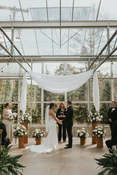 a bride and groom standing at the alter during their wedding ceremony in a glass walled room