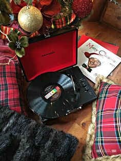 an open record player sitting on top of a wooden floor next to a christmas tree