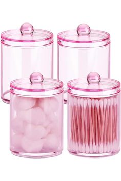 three glass containers with pink cotton swabs in them