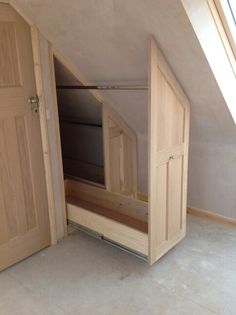 an empty room with two wooden doors and a window in the corner that is open